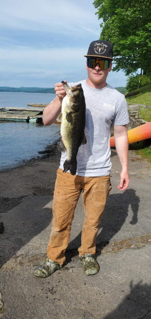 Young man standing on the shoreline with a large fish he caught.