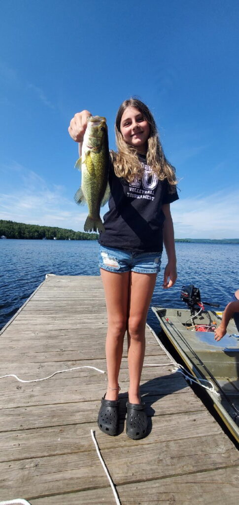 Young girl on a dock, holding out the Trout she caught.